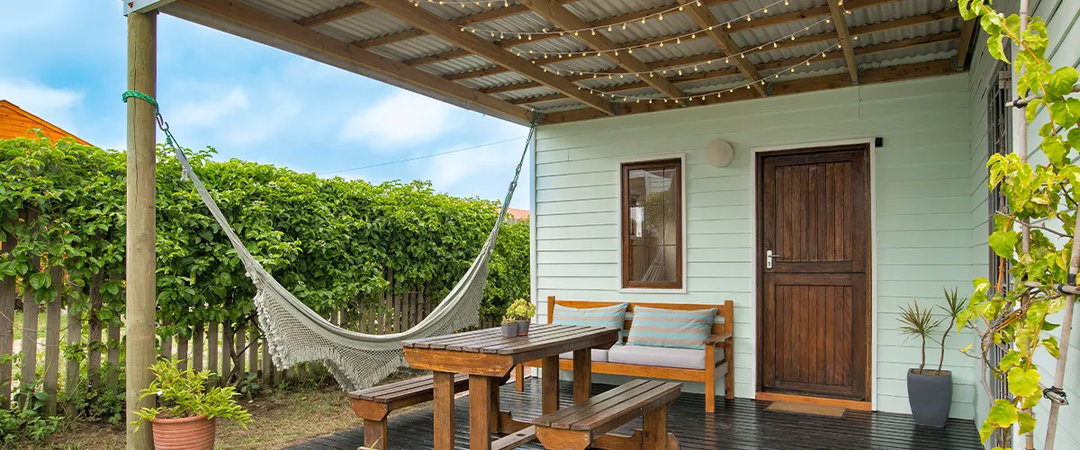 A covered wood deck with a hammock and a table