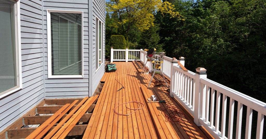 Replacing deck boards on a wood deck with a white railing