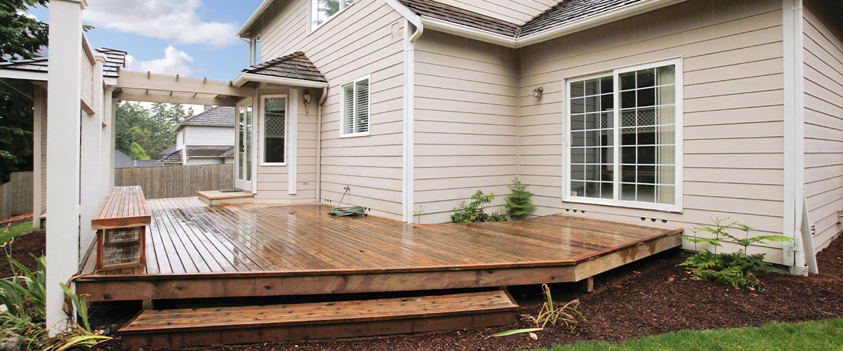 A floating deck on the side of a home with white siding