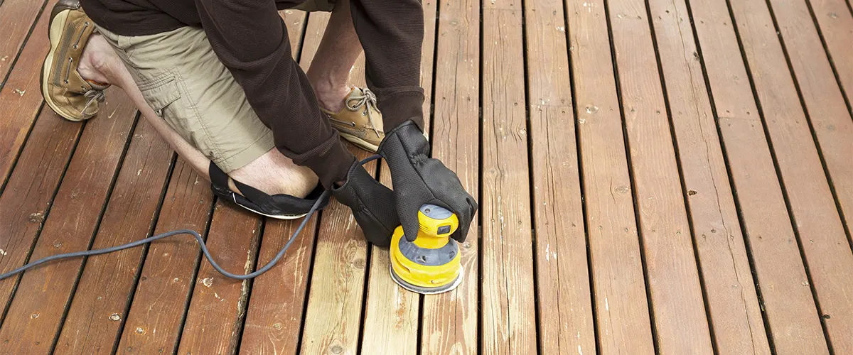 A man sanding a wood deck with a DeWalt sander