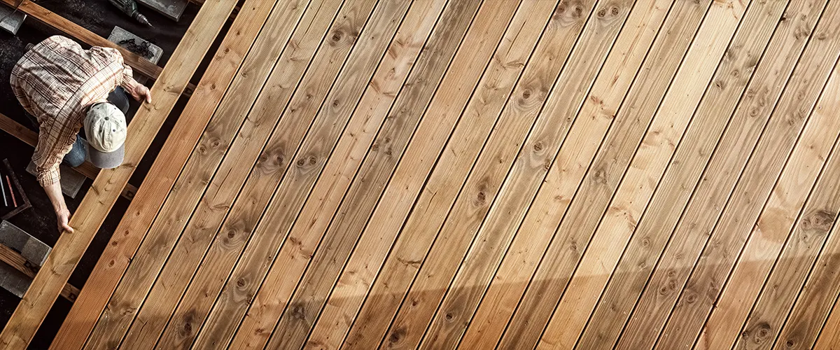 A deck builder installing a composite deck that resembles the wood grain