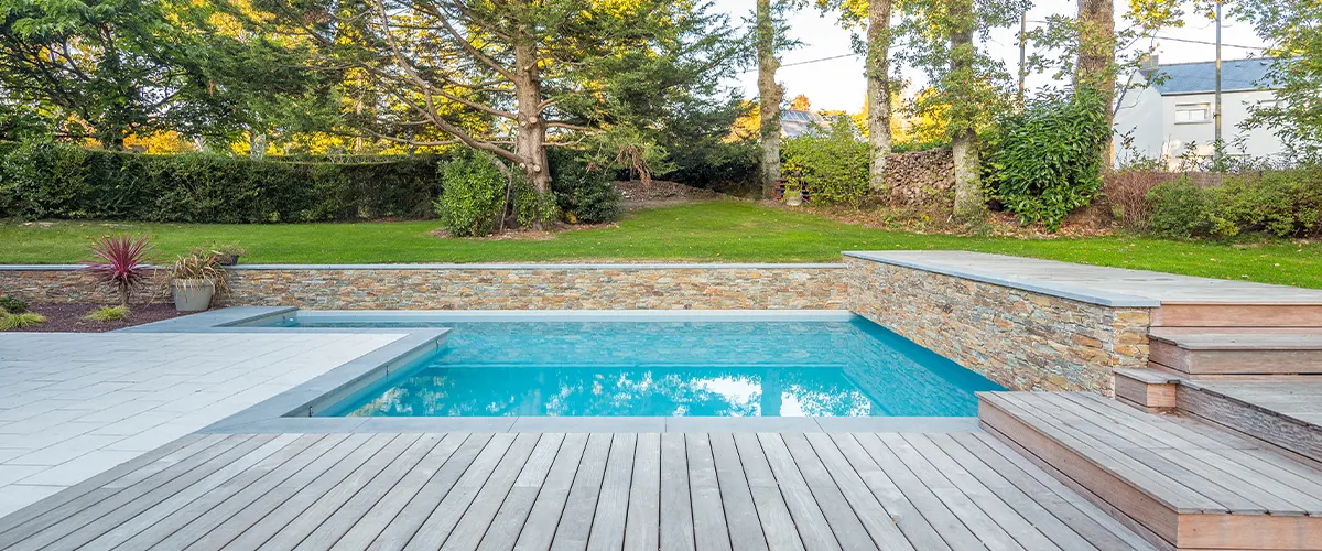 A beautiful pool deck with stone wall