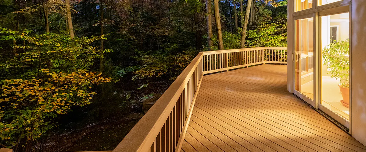 A composite deck with wood railing at night