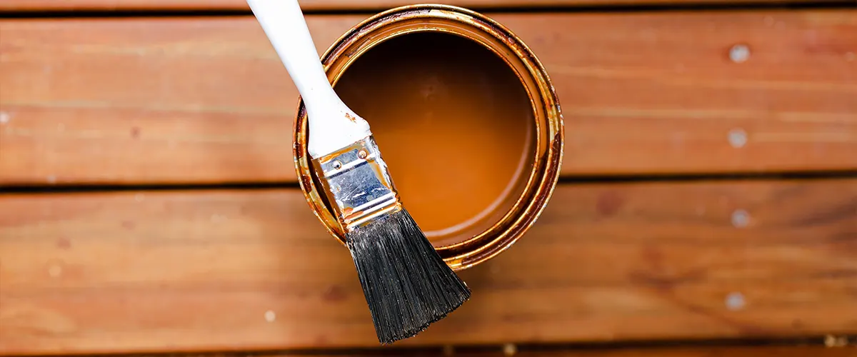 Deck stain in a can and a brush on top of it