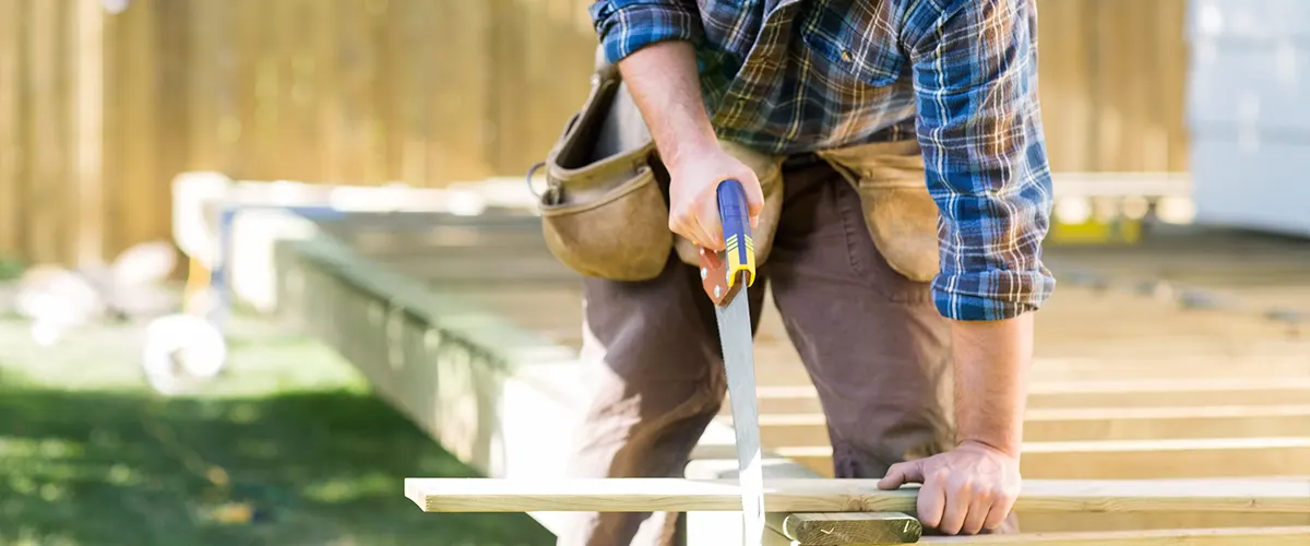 A deck builder cutting a piece of wood