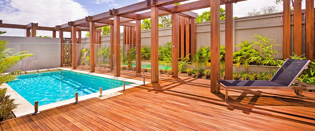 A large pool deck with a wood pergola