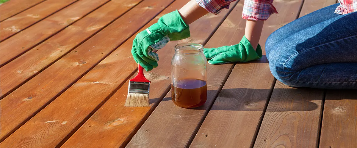 A woman staining a deck with the stain in a jar