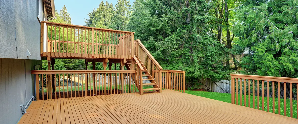 Backyard view of family house with upper and lower decks connected by deck stairs