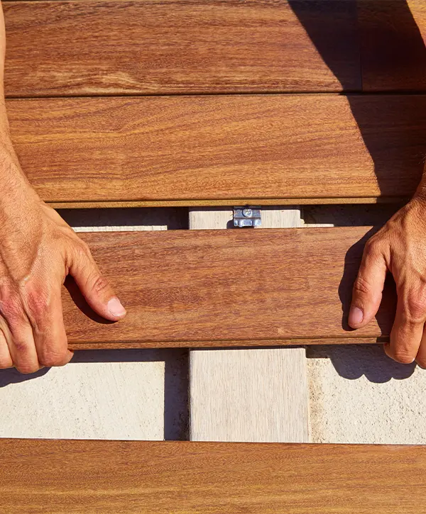 Man placing a wood plank on a deck.
