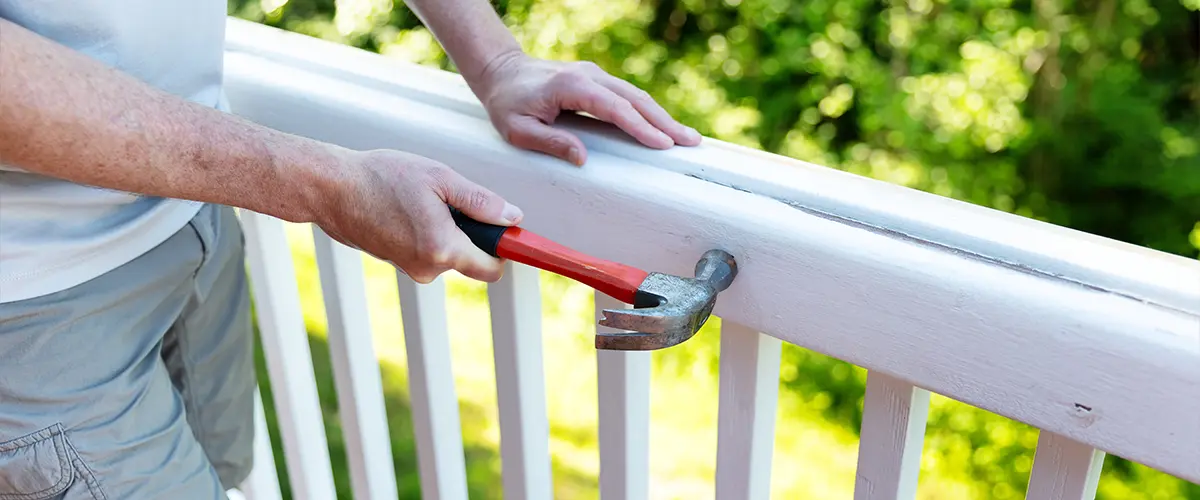 Expert deck railing repair in Knoxville, TN, with a craftsman fixing a white railing.