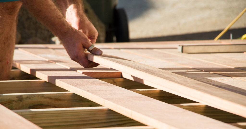 Man placing a plank of wood in a deck home renovation