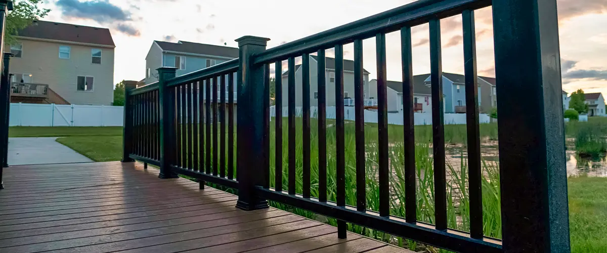 Modern backyard deck in Knoxville, with black metal railing and balusters, overlooking residential neighborhood at sunset - outdoor deck installation.