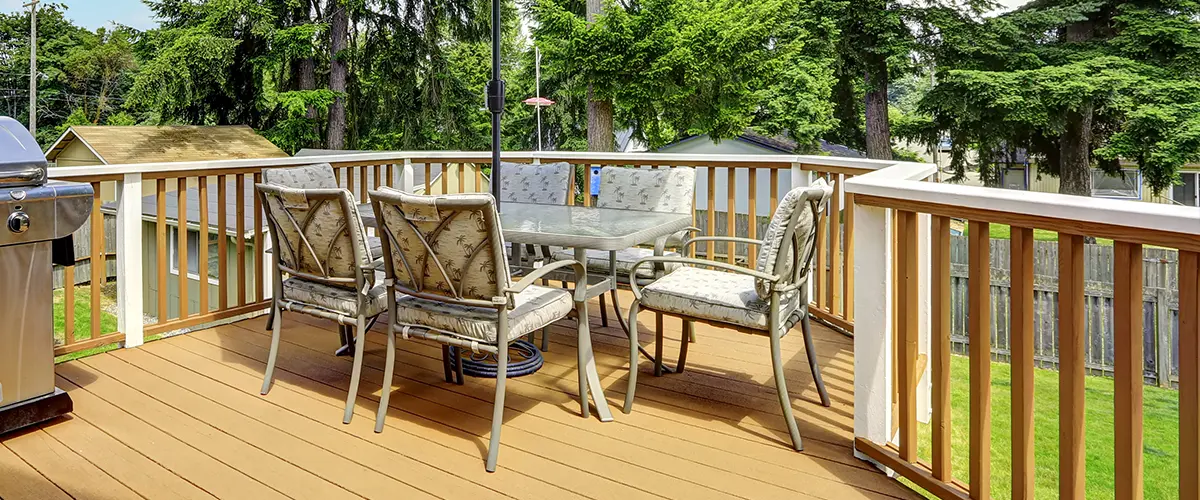 Spacious backyard deck with outdoor dining set, grill, and umbrella surrounded by trees - residential deck with wood deck balusters in Knoxville.