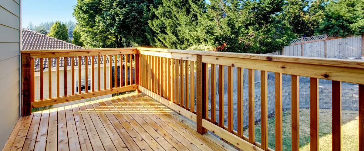 Wooden deck with natural railing overlooking lush backyard landscaping