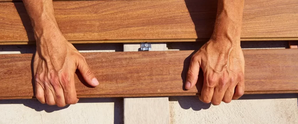 Hands installing wooden deck boards with hidden fasteners