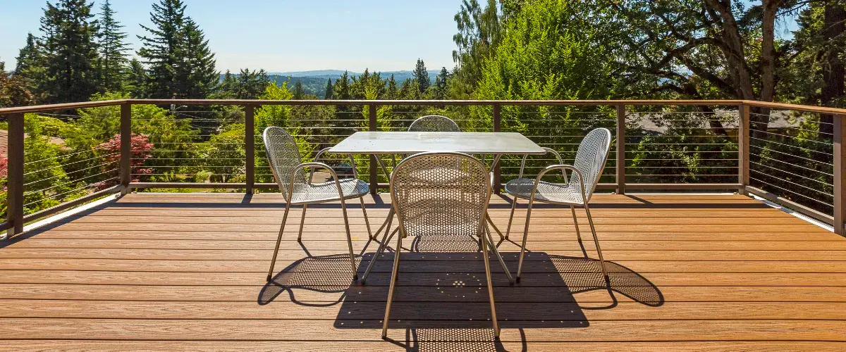 Stylish outdoor deck with metal railing, modern patio furniture, and scenic views of lush green trees and mountains.