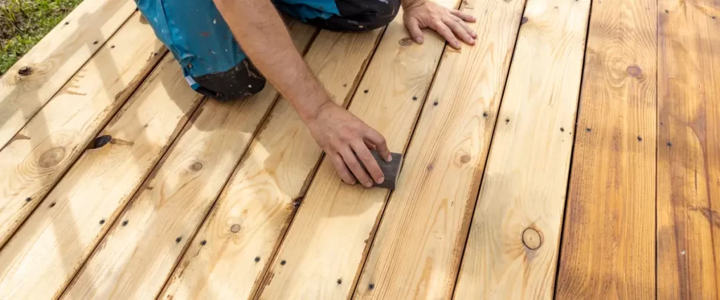 Worker sanding a wooden deck for refinishing