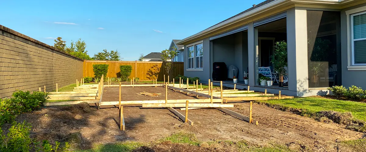 Residential backyard under construction for a floating deck, featuring wooden framework and open space for landscaping.