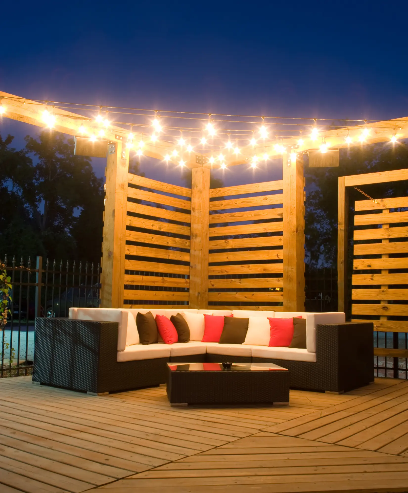 Backyard wooden deck with warm string lights and comfortable seating.