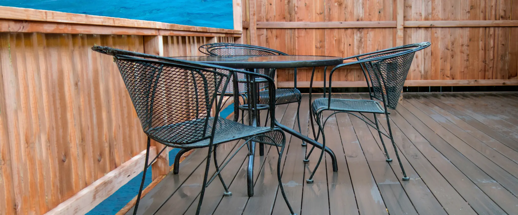 Spacious deck with glass railing overlooking lush greenery.