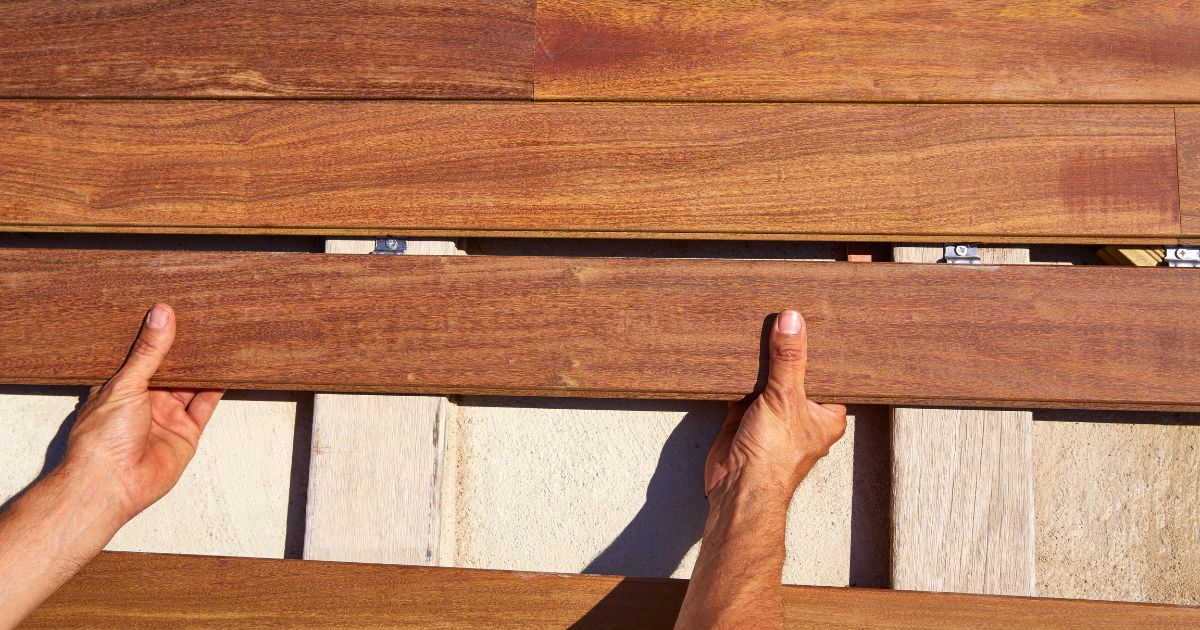 Hands installing wooden deck boards with hidden fasteners