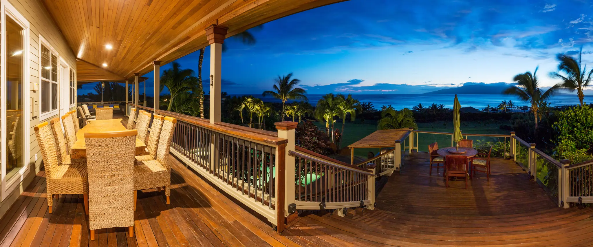 Luxury wood deck with outdoor dining area offering stunning ocean views at sunset