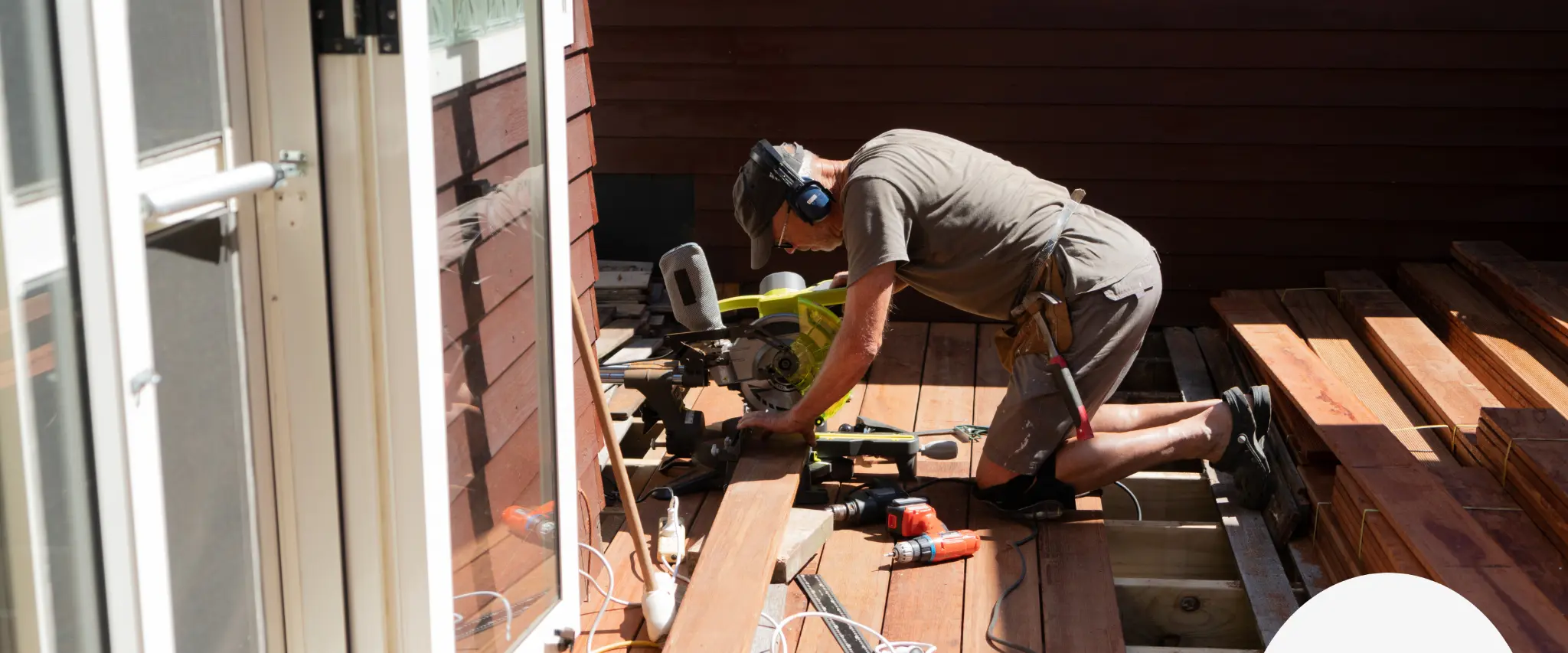 Deck construction process with a worker cutting wooden planks