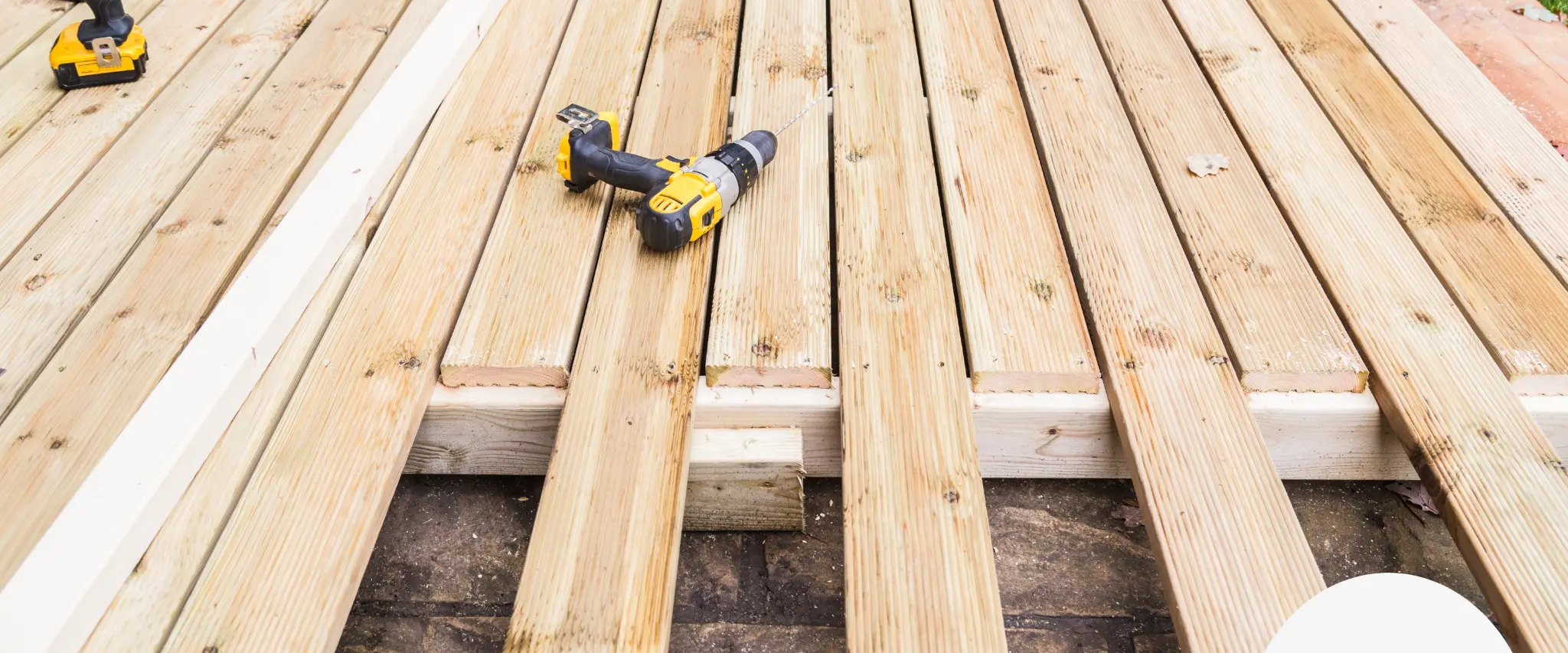 Wood deck under construction with power drill and unfinished planks.