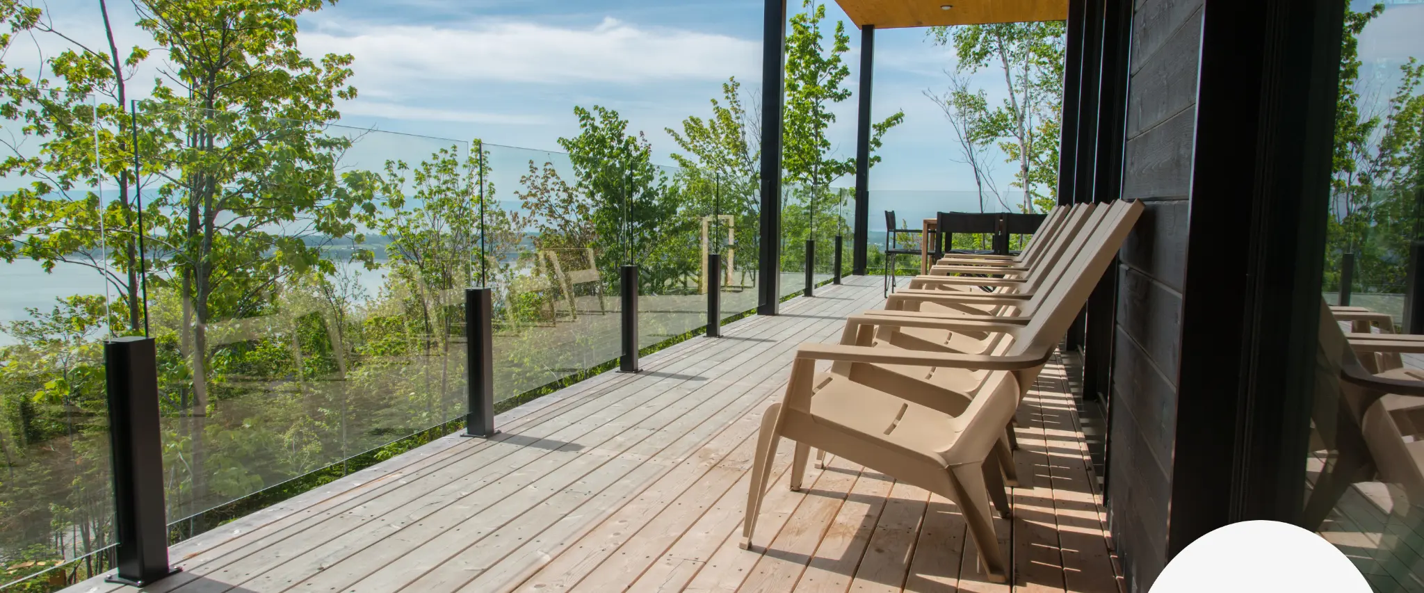 pacious deck with glass railing overlooking lush greenery.