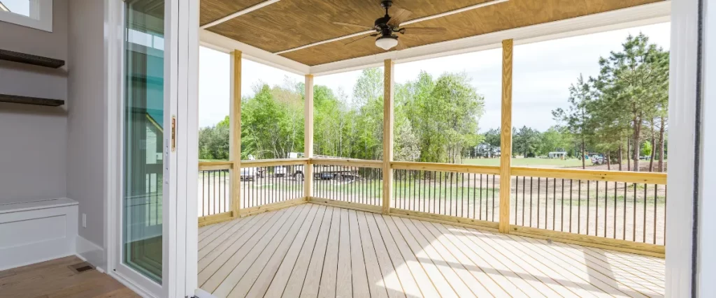 Spacious screened-in porch with wooden flooring and ceiling fan