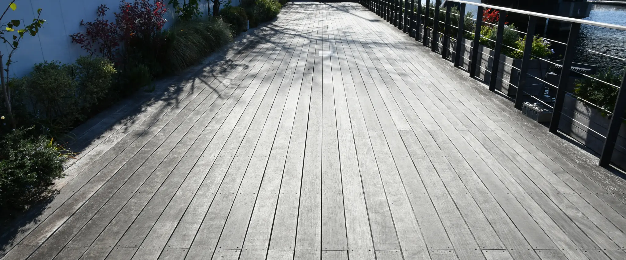 A long weathered wooden decking path with metal railings