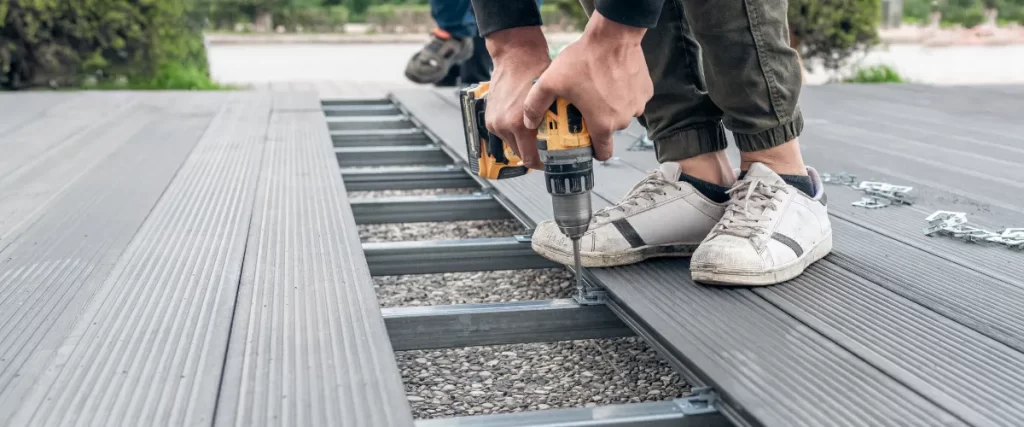 Hands using a drill to install composite decking on a metal frame