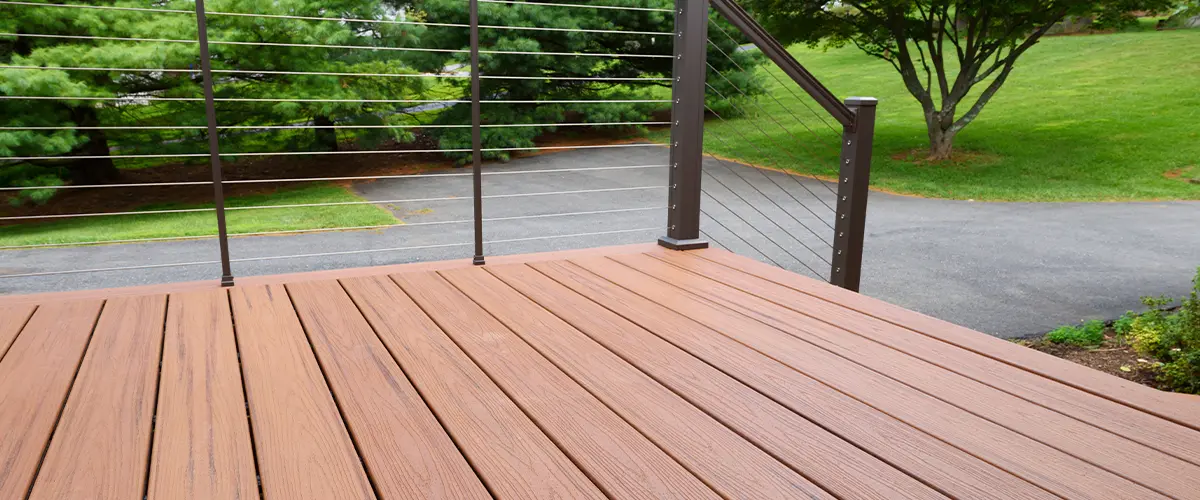 Composite deck with sleek cable railing system overlooking landscaped yard, perfect for durable outdoor living spaces.