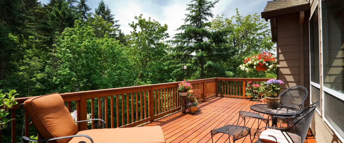 Elevated wood deck with railing and seating surrounded by trees