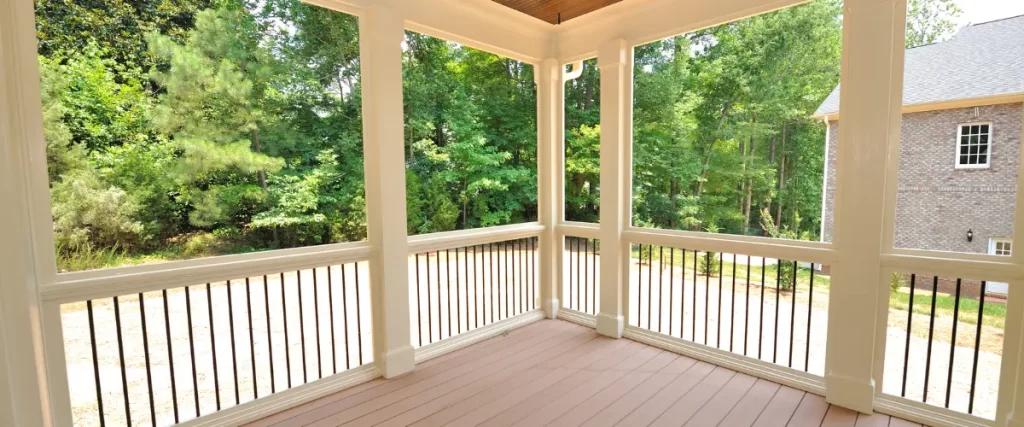 Covered porch with white railings and columns overlooking a green yard