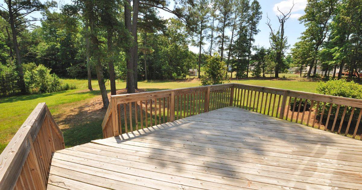 Wood deck with railing overlooking a wooded backyard area