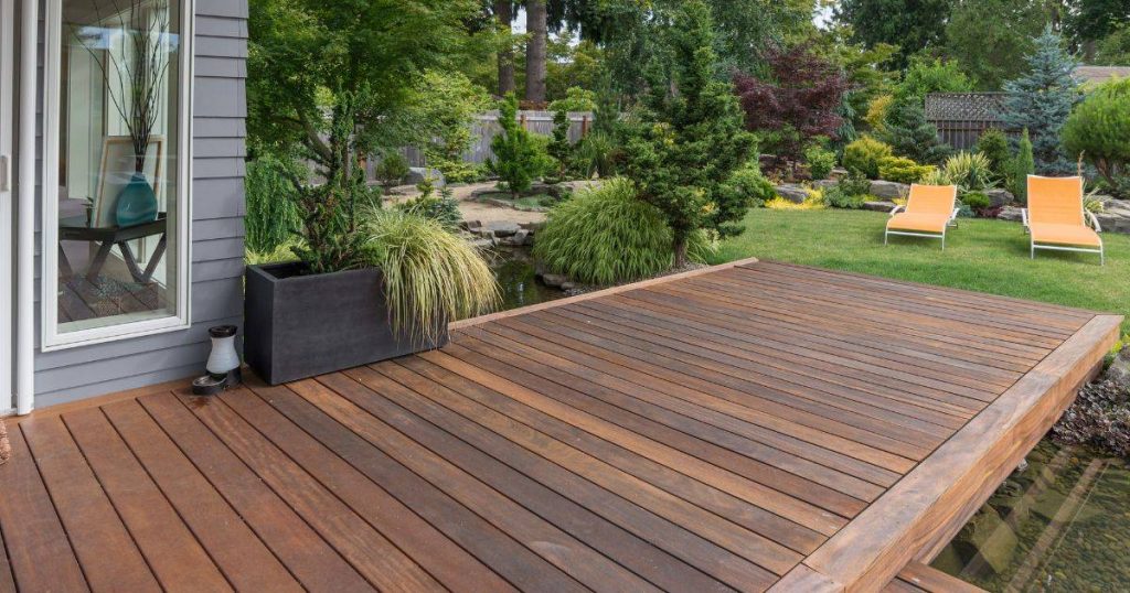 Modern wood deck next to landscaped garden and small pond