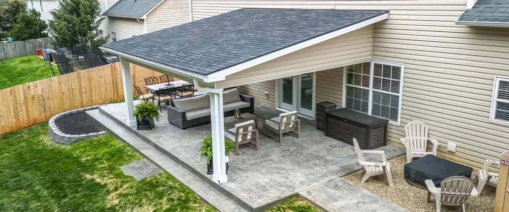 Aerial view of backyard with raised composite deck, paver patio, and landscaped garden -