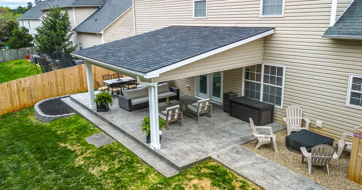 Aerial view of backyard with raised composite deck, paver patio, and landscaped garden - featured