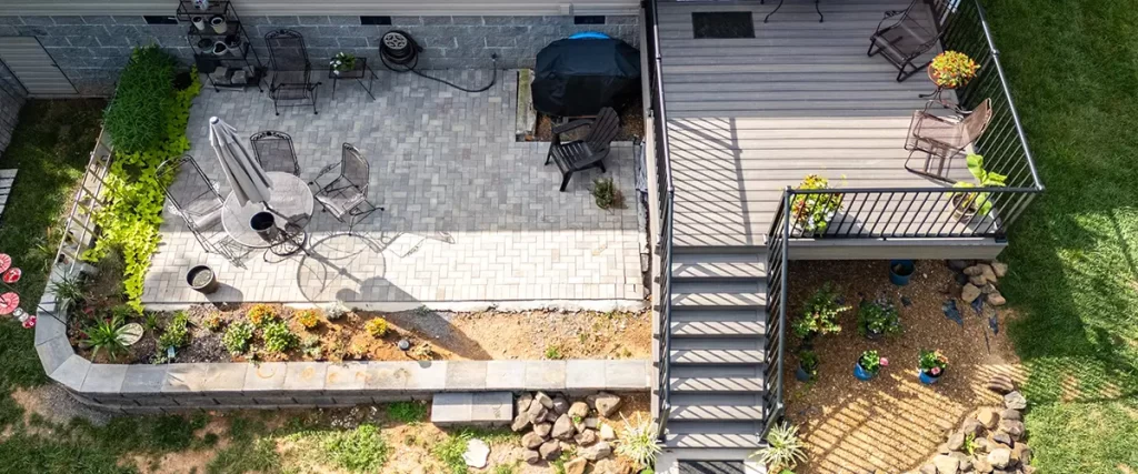 Backyard deck with stairs, paver patio, and landscaping design for outdoor living and entertaining.