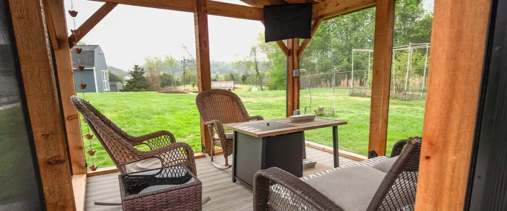 Cozy covered patio with composite decking, outdoor furniture, and stacked stone accents.