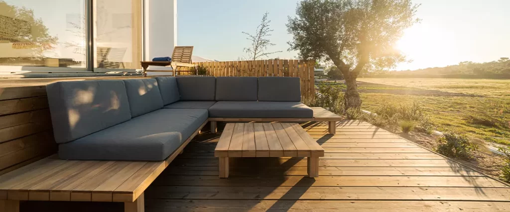 An outdoor wooden deck with grey sofa at sunrise