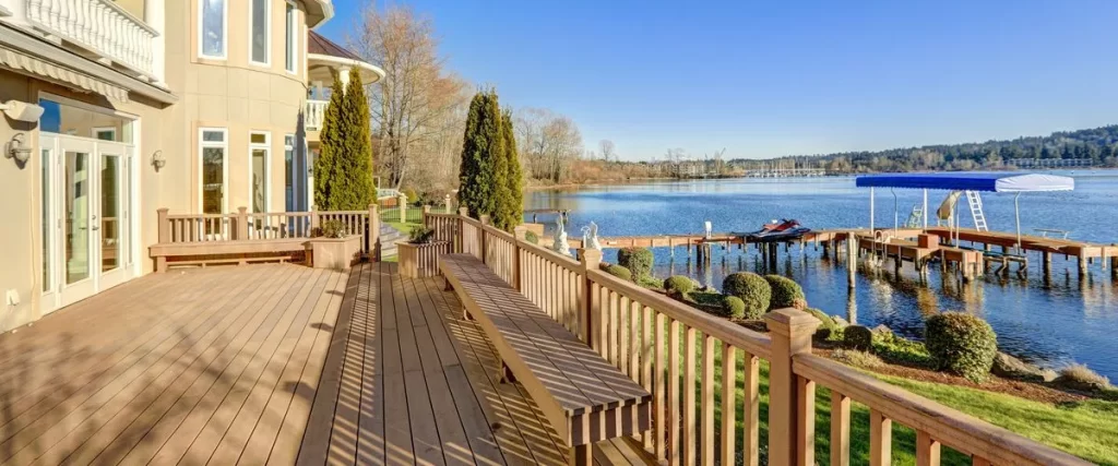 An outdoor deck with a long bench and lake view