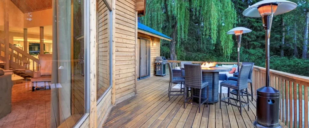 A deck with chairs, lamps, and a fireplace on the middle of a table