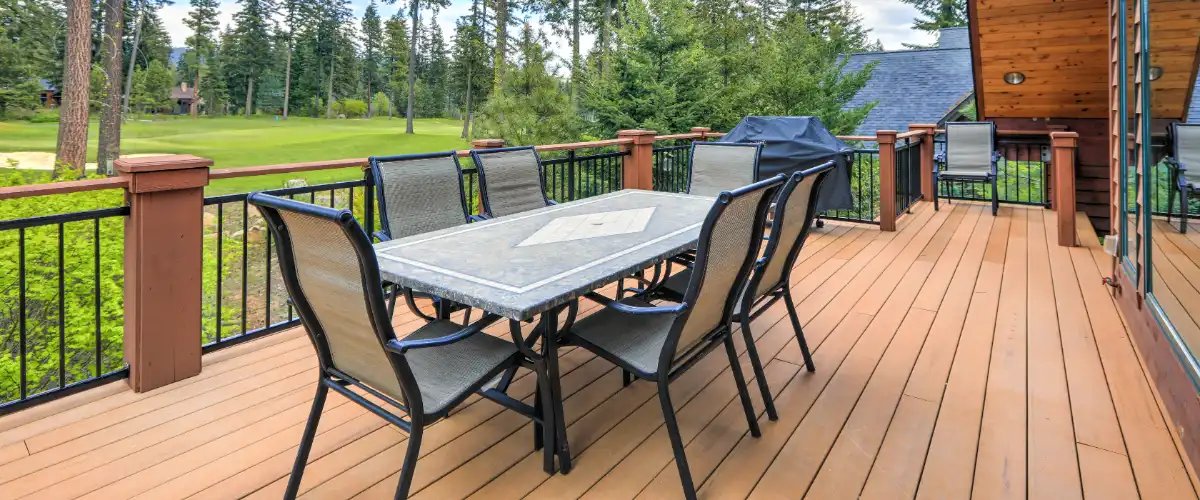 an elevated outdoor deck attached to a building, likely a home or cabin, in a scenic, wooded area