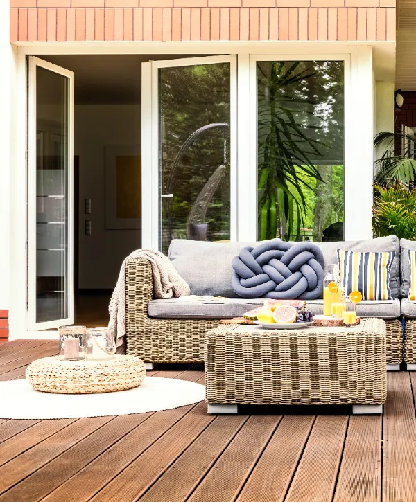 an indoor outdoor deck transition with wicker sofa, armchair, and coffee table