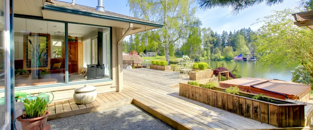 large wooden deck and patio area attached to a house by a lake