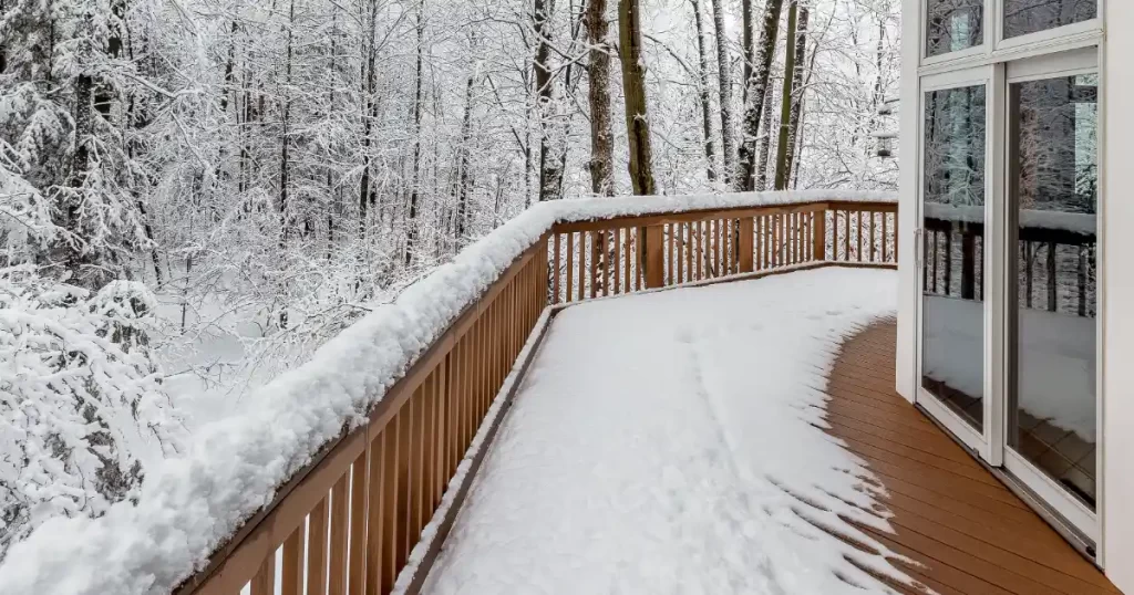 a composite deck covered in snow, overlooking a snow-covered wooded area