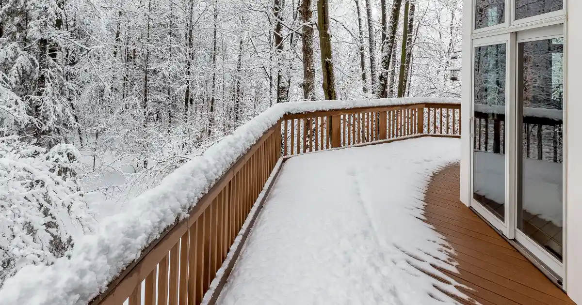 a composite deck covered in snow, overlooking a snow-covered wooded area