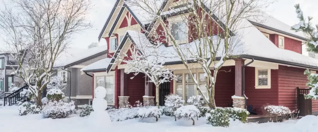 a red house and its surrounding yard covered in snow during winter